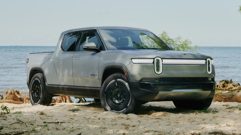 A Rivian R1T pickup truck parked in a seaside environment.