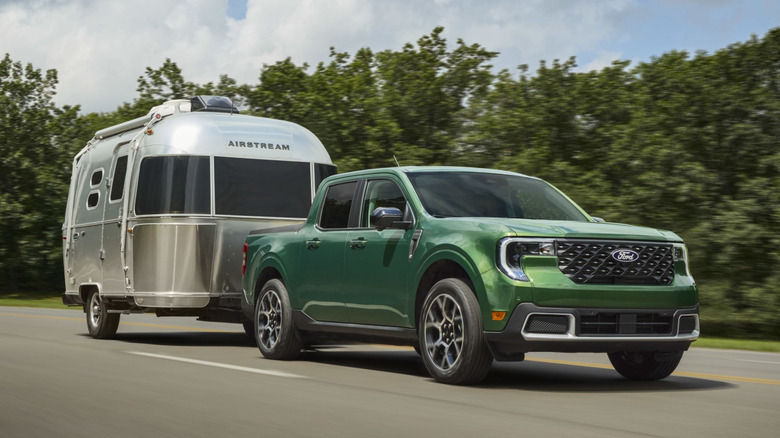 Front 3/4 view of green Ford Maverick towing airstream trailer.