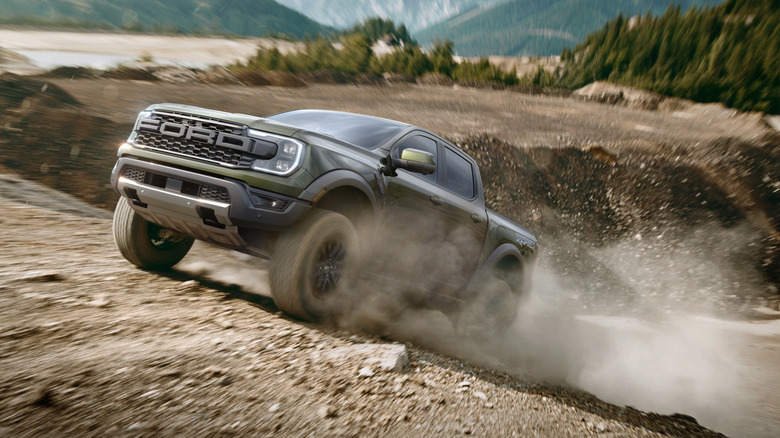 Front 3/4 view of green Ford Ranger Raptor climbing mountain.