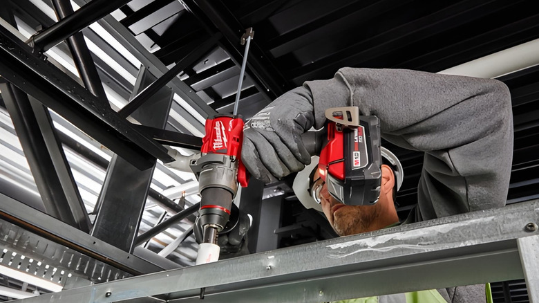 A worker using a Milwaukee tool on a piece of steel.