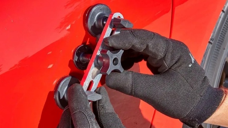 person using dent removal tool on car door