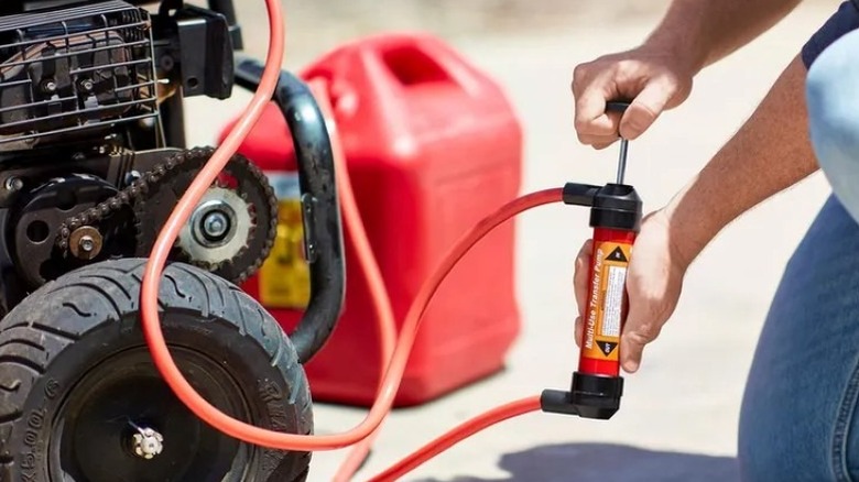 person using hand pump to transfer fuel from container to tool