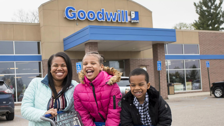 a family smiling in front of a Goodwill store
