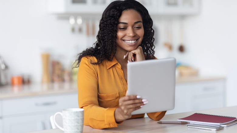 A smiling woman holding a tablet