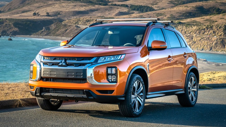 an orange Mitsubishi Outlander Sport parked on a road by the beach
