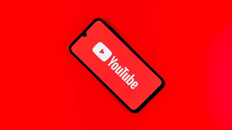 The YouTube logo on a phone, set on a red background.