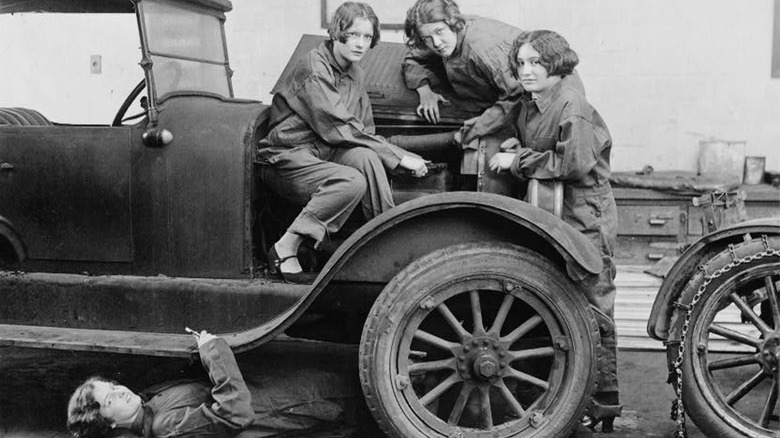 Four girls working on an antique automobile