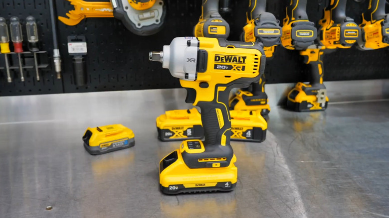 Yellow anbd black DeWalt cordless impact wrench on a metal table in front of several other DeWalt tools.