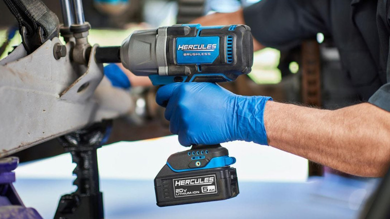 A person using a Hercules blue and black impact wrench to remove a fastener.