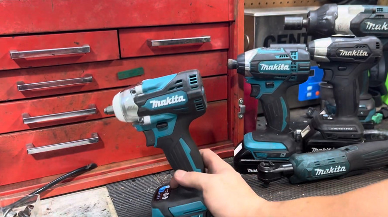 Several blue and black Makita power tools on a tool bench.