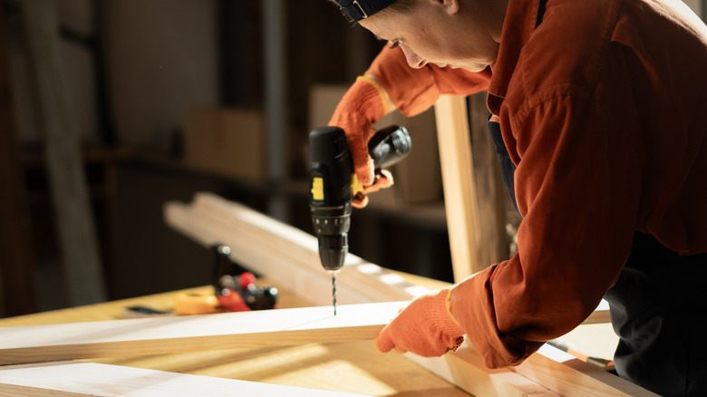 A carpenter using an unbranded cordless drill
