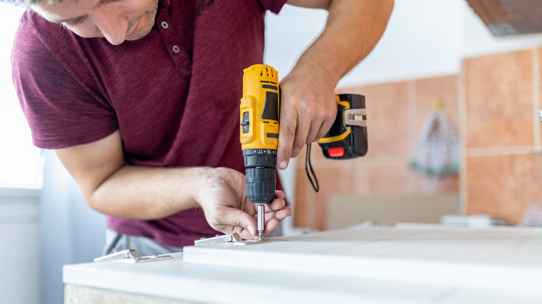 A man assembling furniture by using a cordless screwdriver