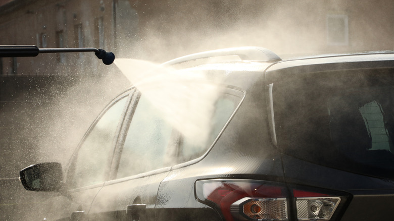 A car being washed by a pressure washer