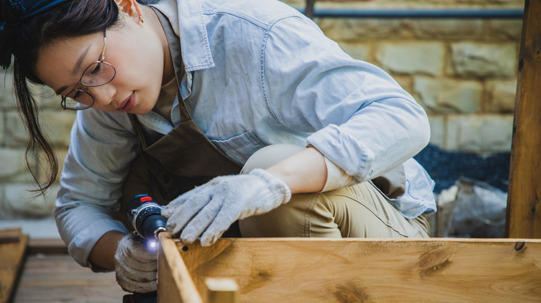 Woman operating a drill on a woodworking project
