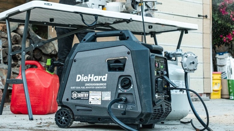DieHard 5,000-watt generator outdoors with person working on a table in the background