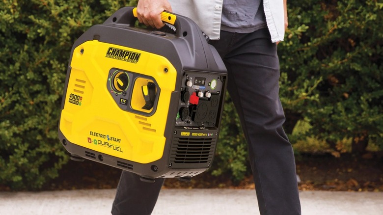 Person carrying a Champion dual-fuel inverter generator by the handle
