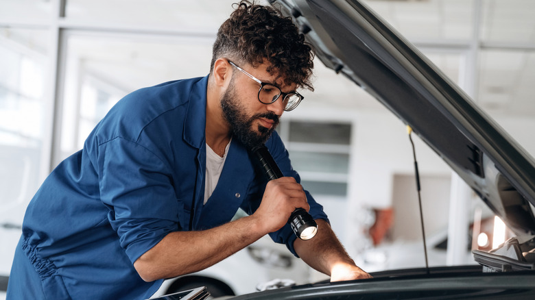 A person looking under the hood of a vehicle.