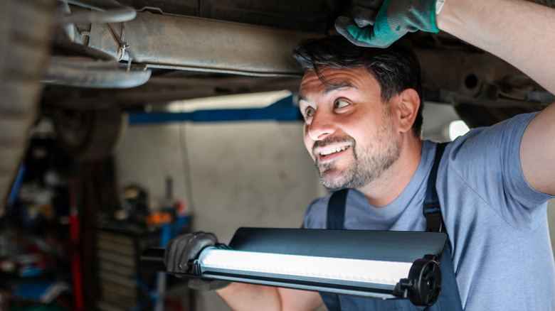 A person using a light bar while working on a car.