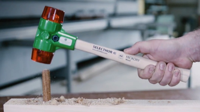 A person using a soft-faced hammer on wood.