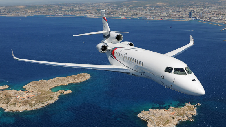 Dassault Falcom 8x jet seen from front right flying above a coastal city