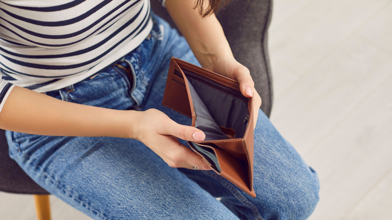 Person opening up brown-colored empty wallet