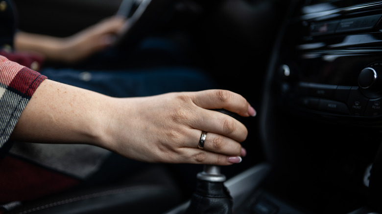 Close-up of a person's hand on a manual shifter knob.