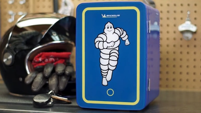 Michelin mini fridge on a garage table with a motorcycle helmet, keys, and gloves next to it