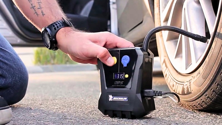 Person using a Michelin Mini Tyre Inflator on a car wheel
