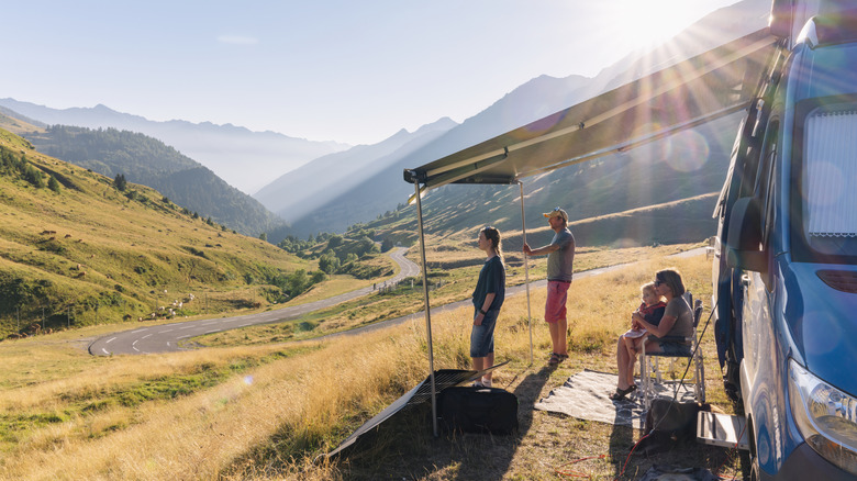 People under an awning next to a camper