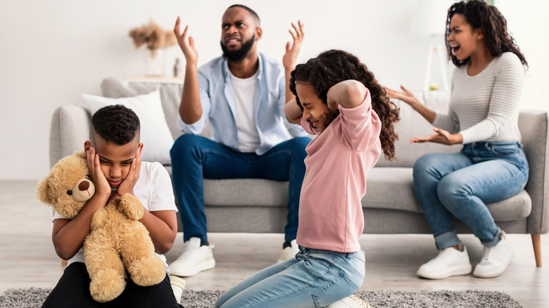 Two Children holding their ears with two adults annoyed in the background.