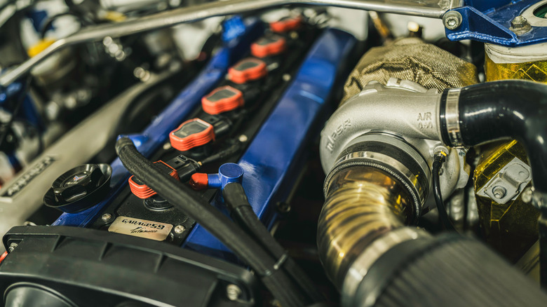 Close-up of Nissan RB-style straight six engine with aftermarket turbo kit, intake, coil pack, and other performance mods