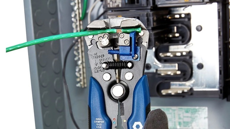 A blue-handled Quinn wire stripper being used to prepare a length of copper wire