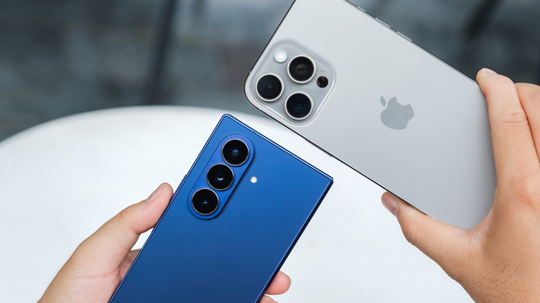 hands holding an iPhone next to an Android phone
