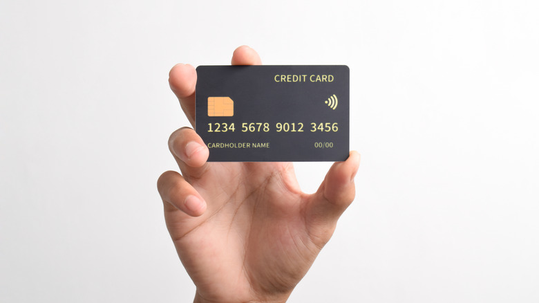 A hand holding up a credit card over a blank background