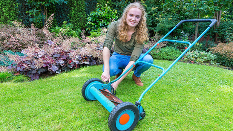 A teenager maintaining a reel mower.