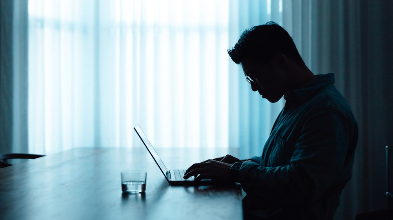 silhouette man working on laptop