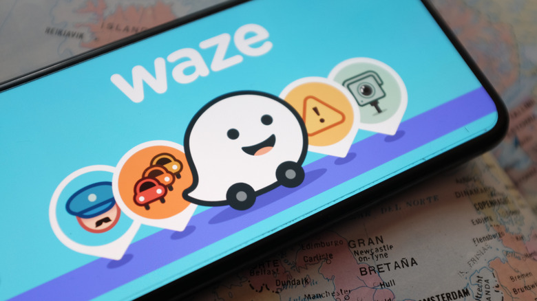 smartphone showing the Waze logo kept on a map
