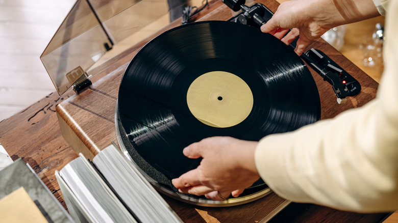 A person putting a vinyl record on a turntable.