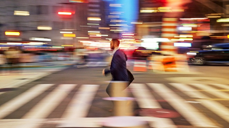 A blurry photo of a person crossing the street at night.