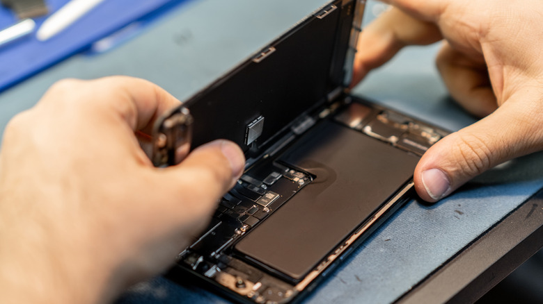 A person repairing a smartphone by opening the screen.