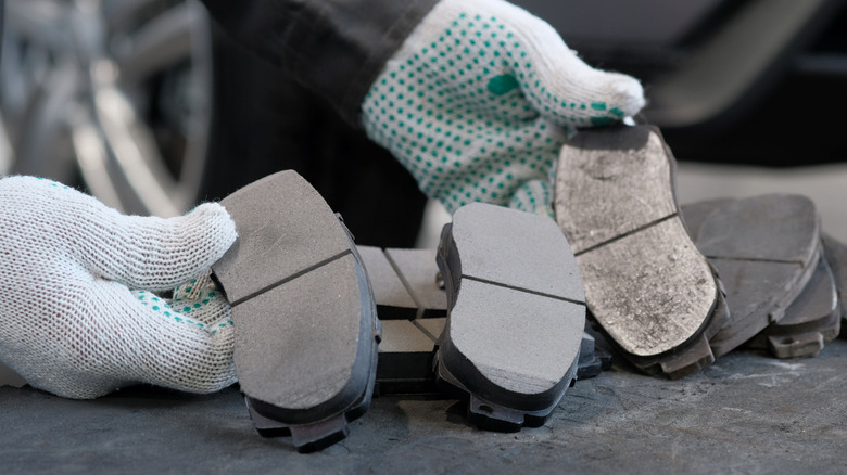 Mechanic holding brake pads of a car of differing conditions