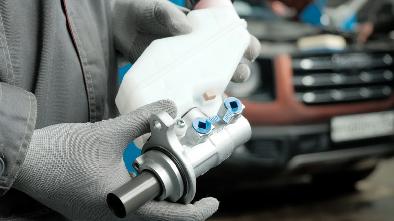 A mechanic holding the master cylinder of a brake system