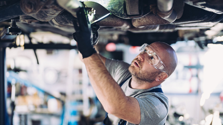 A mechanic looking at bottom of car
