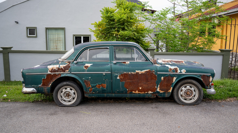 A vehicle in rough shape with rust and flat tires