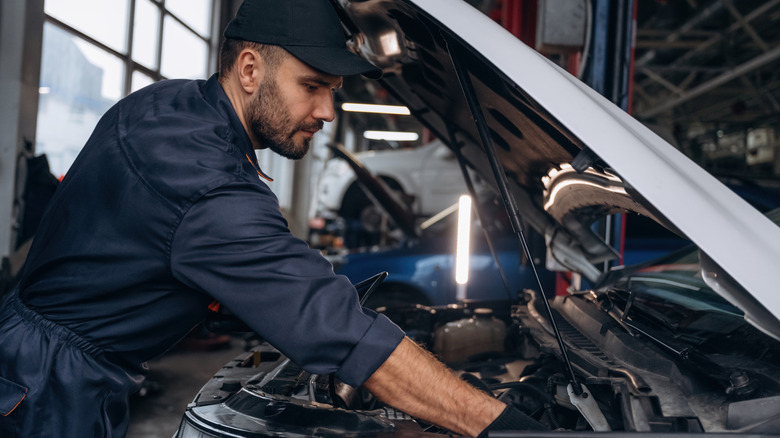 A man looking at car engine at garage