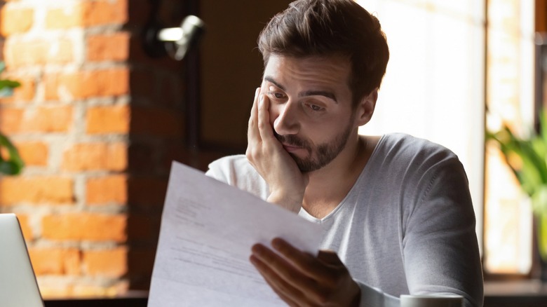 A man looking at a document with distress