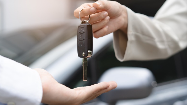 Two hands exchanging a car key