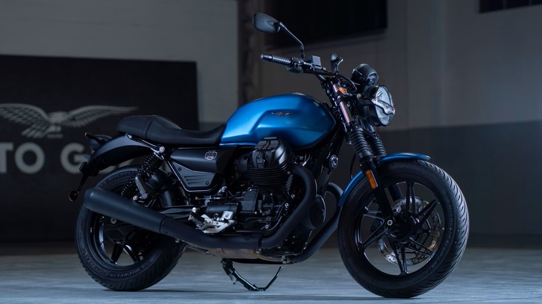 A Moto Guzzi V7 Stone parked in front of the official Moto Guzzi garage