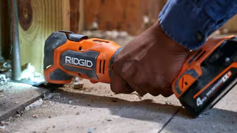 A person using a Ridgid multi-tool on the ground.