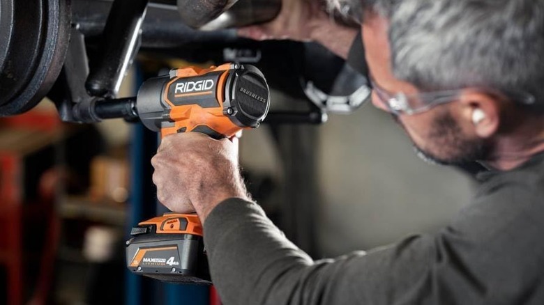 A person using a Ridgid impact wrench on a vehicle.